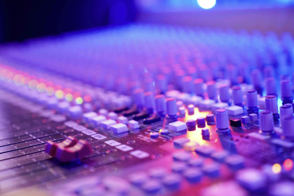 Detailansicht eines Mischpults mit bunten Lichtern und Reglern.