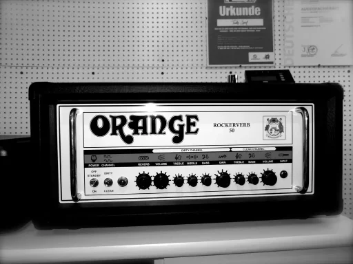 Ein schwarzer Verstärker mit orangefarbenem Logo und Drehreglern.