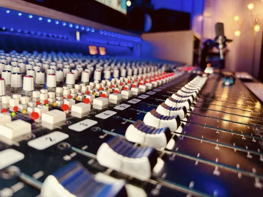 Tonmischpult mit Reglern und Lichtern in einem Studio-Setting.
