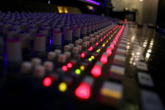 Mixertasten mit leuchtenden Reglern in einem Studio, farblich sortiert.
