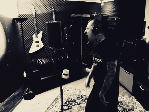 Ein Sänger im Studio, der in ein Mikrofon singt, umgeben von Musikinstrumenten.