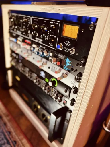 Eine Reihe von Audiogeräten in einem Rack, darunter Regler und Anzeigen.