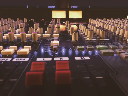 Ein Mischpult mit bunten Reglern und Tasten in schwachem Licht.