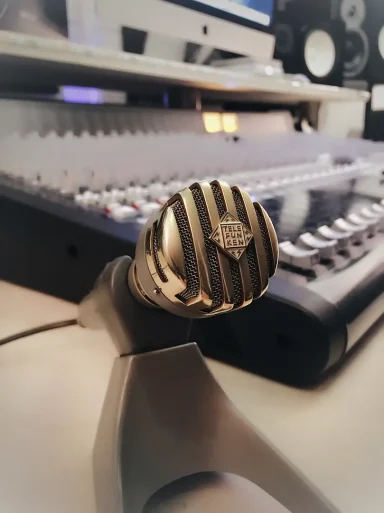 Mikrofon auf einem Mischpult mit Reglern im Hintergrund.