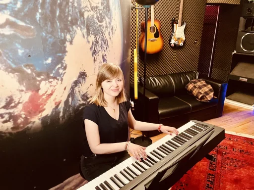 Frau spielt auf einem Keyboard in einem musisch eingerichteten Raum mit Gitarren.