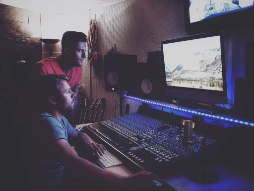 Zwei Personen konzentriert beim Arbeiten an einem Musikproduktionscomputer.