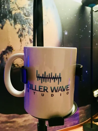 Tasse mit dem Logo „Killer Wave Studios“ vor einem planetarischen Hintergrund.
