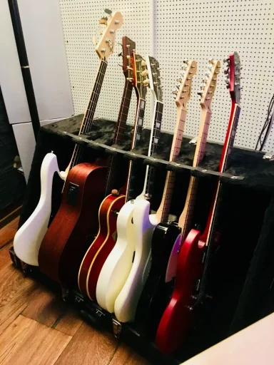 Reihe von verschiedenen E-Gitarren in einem Rack, darunter auch eine weiße und eine rote.