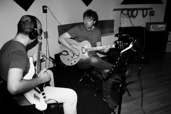 Zwei Musiker im Studio, einer spielt Gitarre, der andere E-Bass.