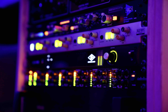 Geräte in einem Rack mit leuchtenden Reglern und Anzeigen in lila Beleuchtung.