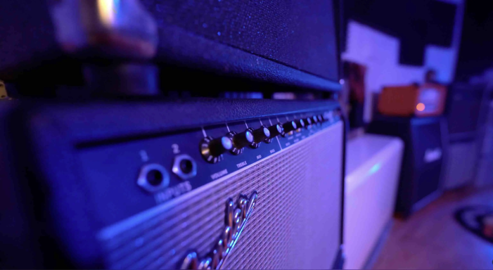 Nahaufnahme eines Gitarrenverstärkers mit Schaltern und Reglern in blauer Beleuchtung.