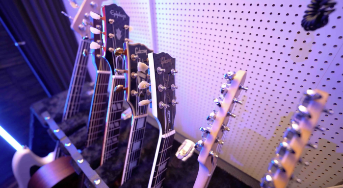 Reihe von E-Gitarren auf einem Gitarrenständer vor einer Wand mit Lochplatte.